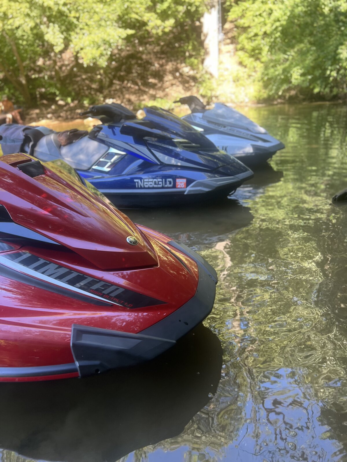 Red Yamaha WaveRunner Limited and blue Yamaha jet skis floating in a quiet cove